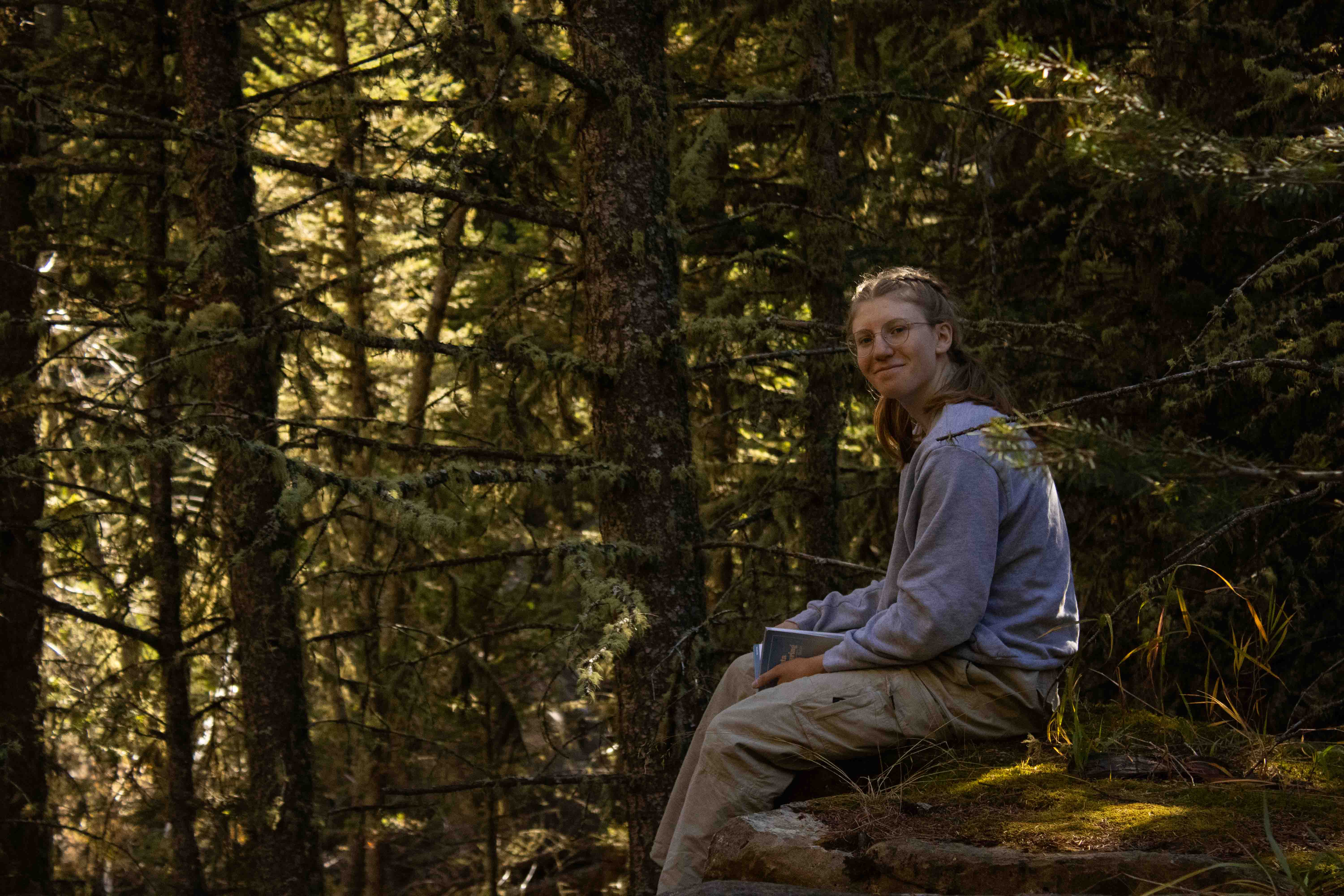 Photo of a model in the woods sitting on a rock